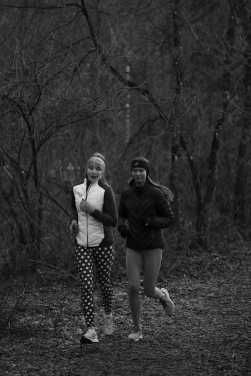 Due persone corrono lungo un sentiero nel bosco